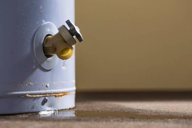 A low angle close-up view of a leaking faucet on a domestic water heater A low angle close-up view of water leaking from the plastic faucet on a residential electric water heater sitting on a concrete floor in the basement. Water Heater Problems stock pictures, royalty-free photos & images