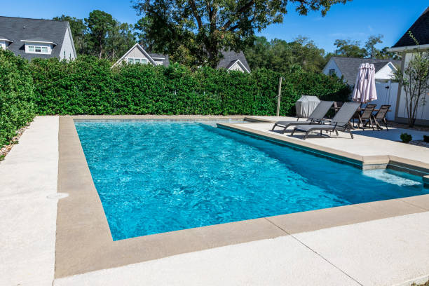 A rectangular new swimming pool with tan concrete edges in the fenced backyard of a new construction house A rectangular new swimming pool with tan concrete edges in the fenced backyard of a new construction house with privacy hedges. pool stock pictures, royalty-free photos & images