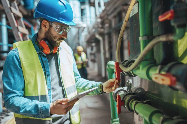 Checking everything twice A young Caucasian male engineer is examining the pipe system and checking the data on his tablet. plumbing stock pictures, royalty-free photos & images