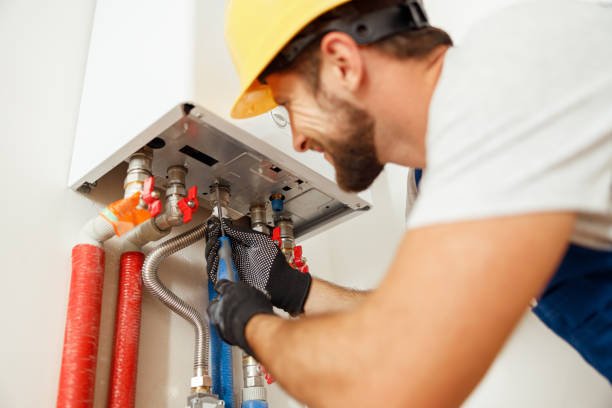 Closeup of plumber using screwdriver while fixing boiler or water heater, working on heating system in apartment Closeup of plumber using screwdriver while fixing boiler or water heater, working on heating system in apartment. Manual work, maintenance, repair service concept plumbing stock pictures, royalty-free photos & images