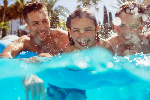 Father swimming with his two children in swimming pool  pool stock pictures, royalty-free photos & images