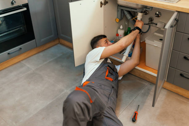 Just need to untighten this A young Caucasian plumber is lying down and changing a pipe under a kitchen sink, with a screwdriver next to him. plumbing stock pictures, royalty-free photos & images