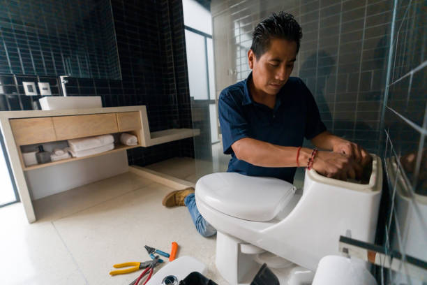 Latin American plumber fixing a toilet in the bathroom Latin American plumber fixing a toilet in the bathroom - home repair concepts plumber stock pictures, royalty-free photos & images