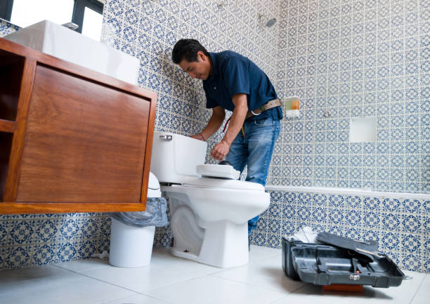 Latin American plumber fixing a toilet in the bathroom Latin American plumber fixing a toilet in the bathroom - home repair concepts plumbing stock pictures, royalty-free photos & images