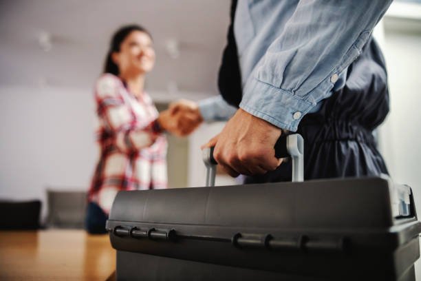 Nurse sitting at home, holding syringe with cure and giving advices over internet. Woman shaking hands with a repairman while standing at home. plumbing stock pictures, royalty-free photos & images