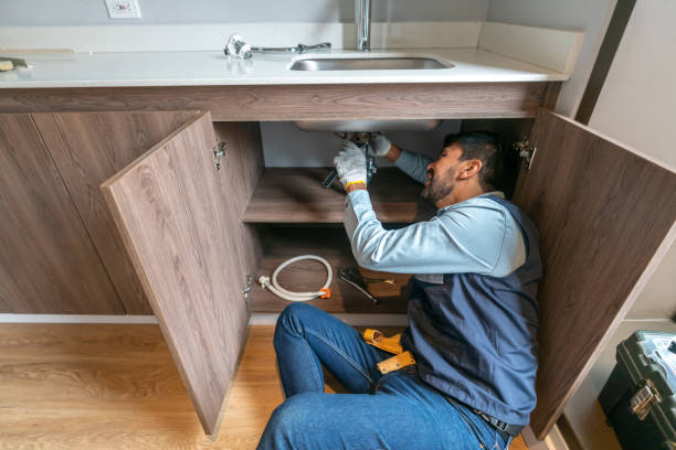 Plumber fixing a leak in the kitchen sink of a house Latin American plumber fixing a leak in the kitchen sink of a house - domestic life Leaky Faucets and Fixtures stock pictures, royalty-free photos & images