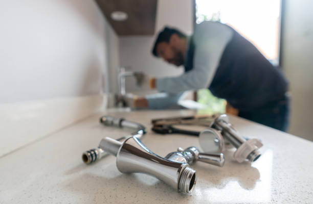 Plumber fixing a leak in the kitchen sink of a house Latin American plumber fixing a leak in the kitchen sink of a house - focus on his tools plumbing stock pictures, royalty-free photos & images