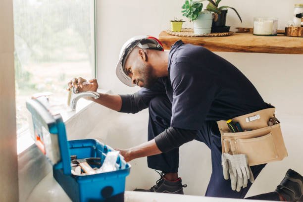 Plumber fixing a leaking bathroom faucet African male plumber looking at leaking bathroom tap. Professional handyman trying to fix a bathroom faucet. plumbing stock pictures, royalty-free photos & images