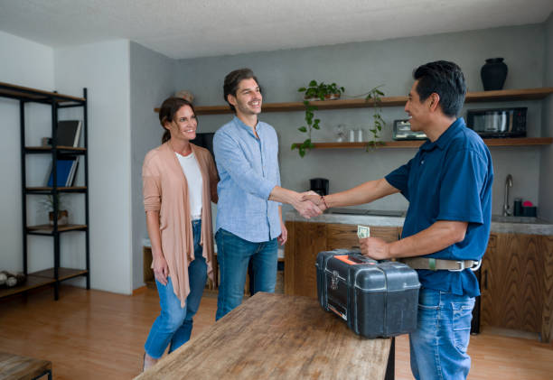 Plumber greeting happy clients at home with a handshake Latin American plumber greeting a couple of happy clients at home with a handshake plumbing stock pictures, royalty-free photos & images