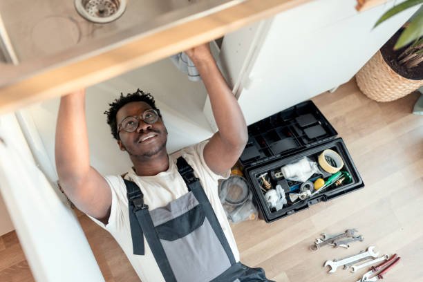 Plumber working on pipes under sink Plumber fixing a leak in the kitchen sink of a house plumbing stock pictures, royalty-free photos & images