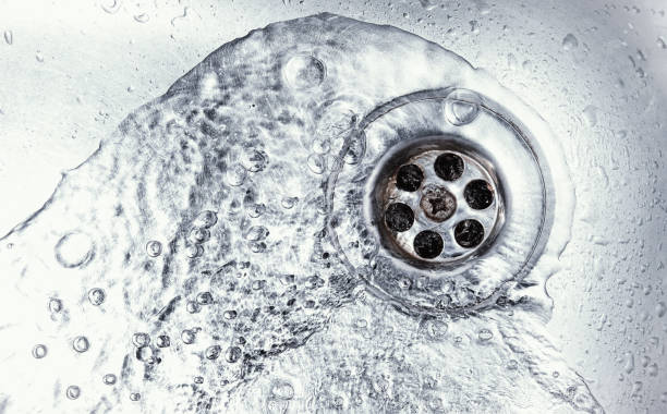 sink hole water drain down on stainless steel kitchen sink hole. top view sewer in washbasin. household plumbing. cleaning and hygiene concept. drain cleaning stock pictures, royalty-free photos & images