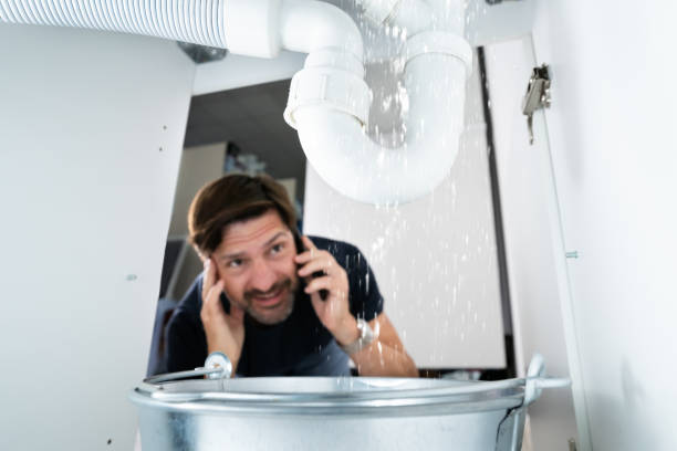 Worried Man Calling Plumber Worried Man Calling Plumber While Watching Water Leaking From Sink plumbing stock pictures, royalty-free photos & images