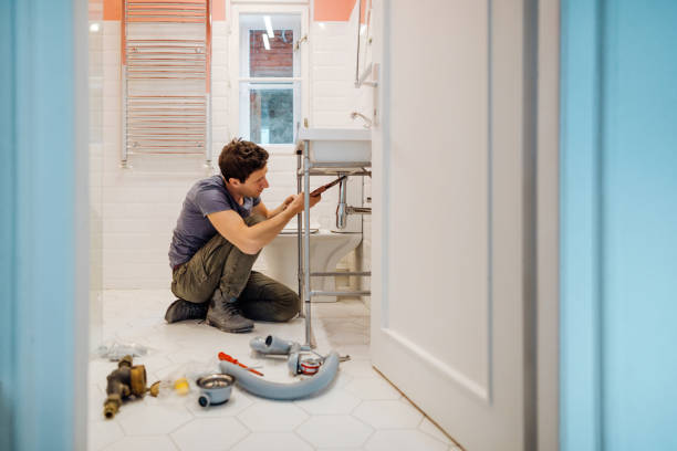 Young man fixing a leak under the bathroom sink Young man fixing a leak under the bathroom sink plumbing stock pictures, royalty-free photos & images